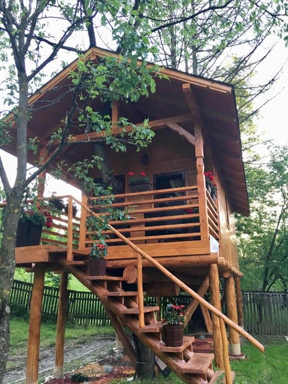 a tree house with a deck and potted plants at Domeniul Horj Casa din Cireș Moisei in Moisei