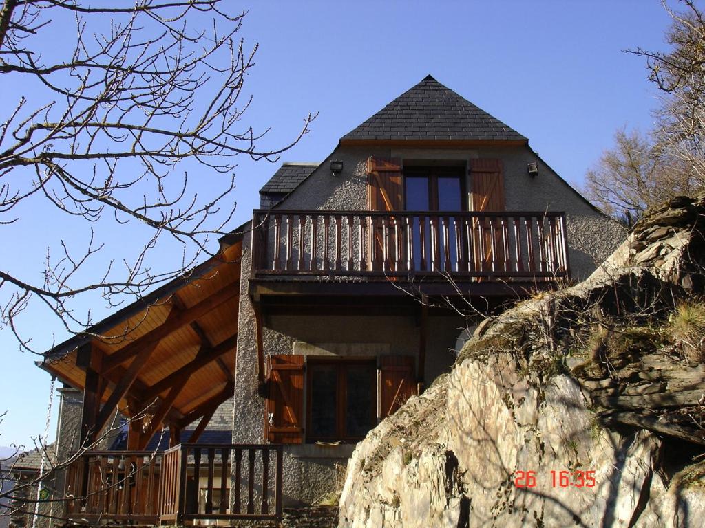 uma casa sobre uma rocha com uma varanda em gîte Vallée des Nestes em Bareilles