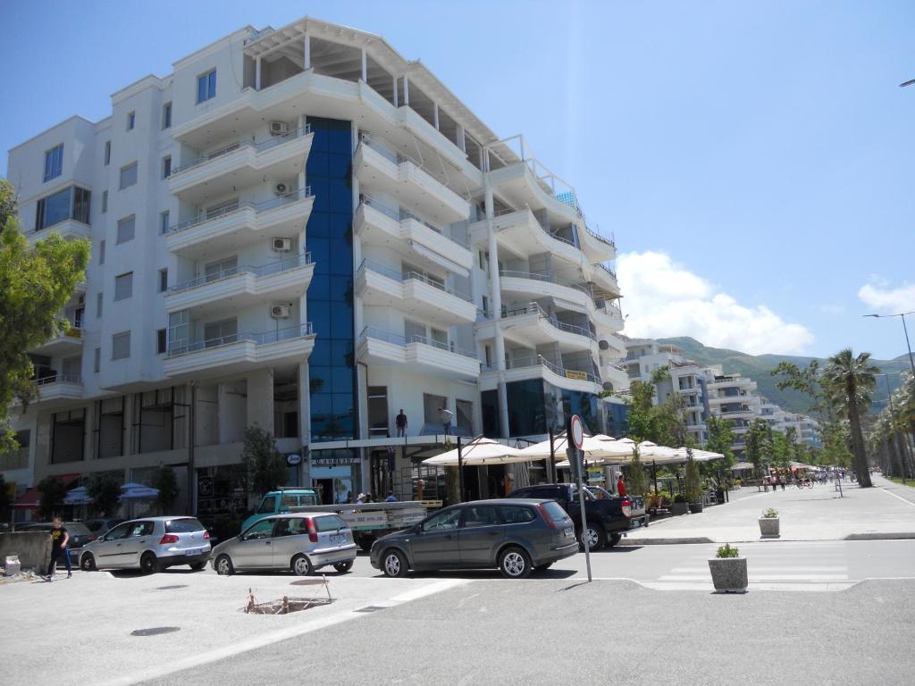 a large apartment building with cars parked in a parking lot at Lungomare Apartament Sea View in Vlorë