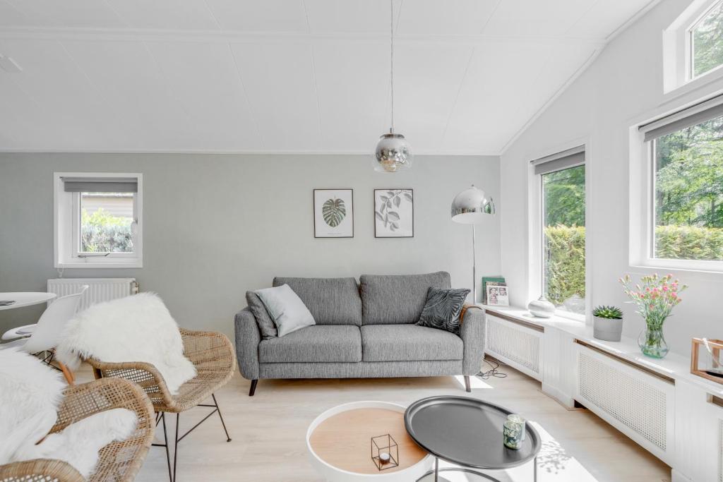 een woonkamer met een bank en stoelen bij Chalet Descansar op de Veluwe in Beekbergen