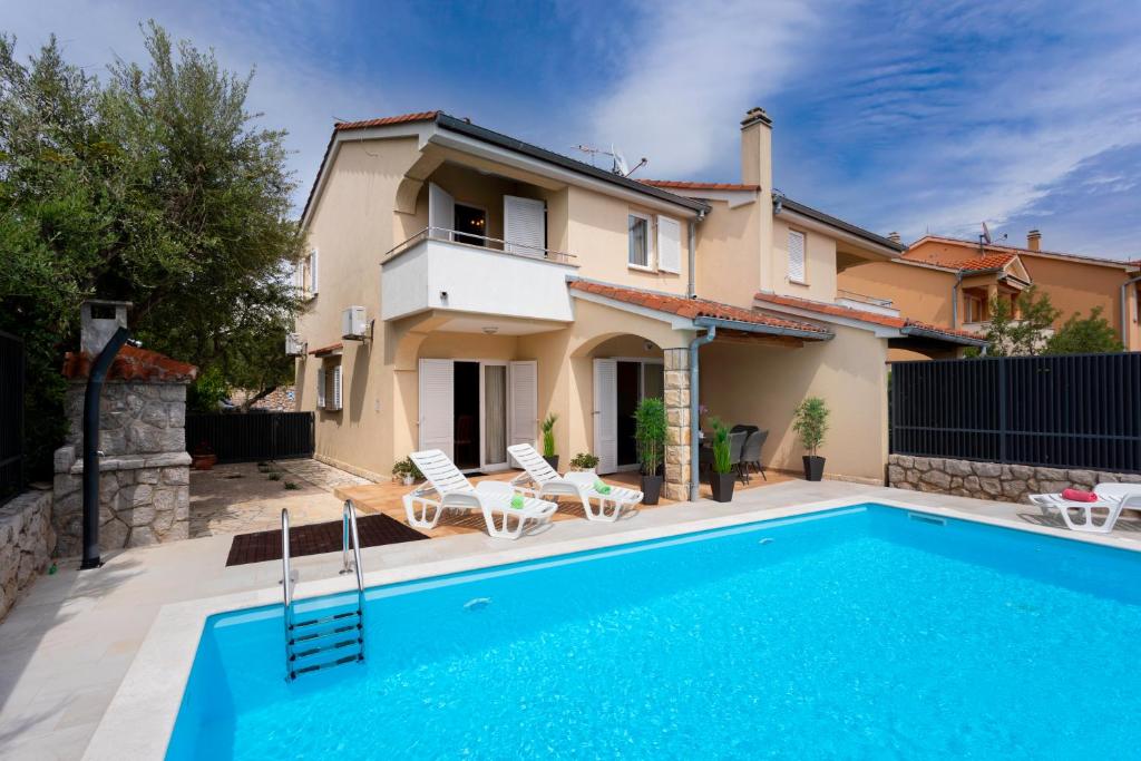 a villa with a swimming pool in front of a house at Villa Pianka in Krk