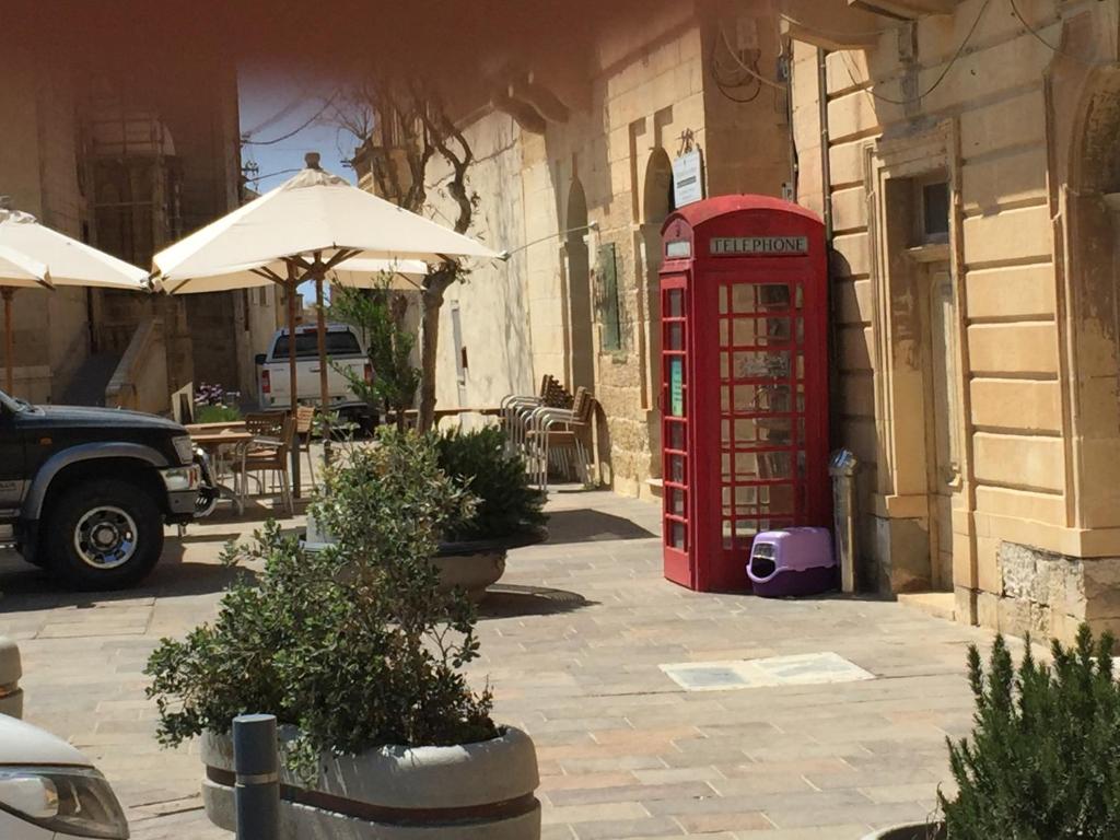 una vecchia cabina telefonica rossa accanto a un edificio di Ta’ Lorenzo a San Lawrenz