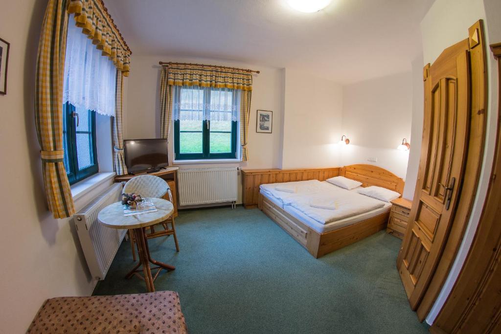 a bedroom with a bed and a table and a desk at Pension Pohoda in Špindlerův Mlýn