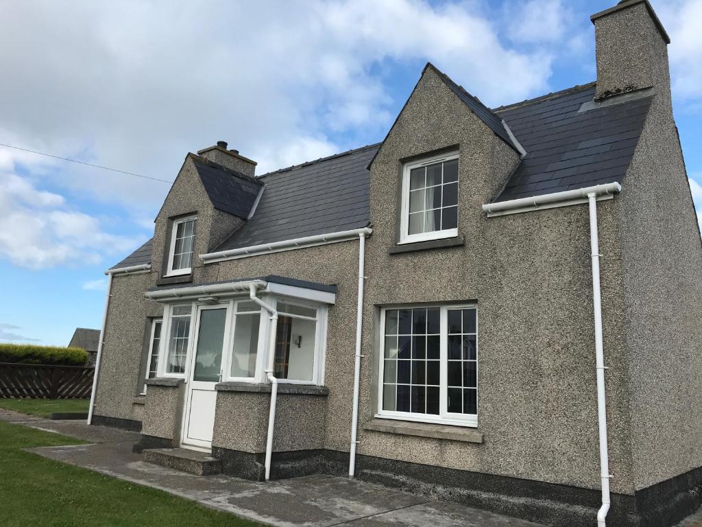a gray house with white windows and a roof at 14 Upper Bayble in Stornoway