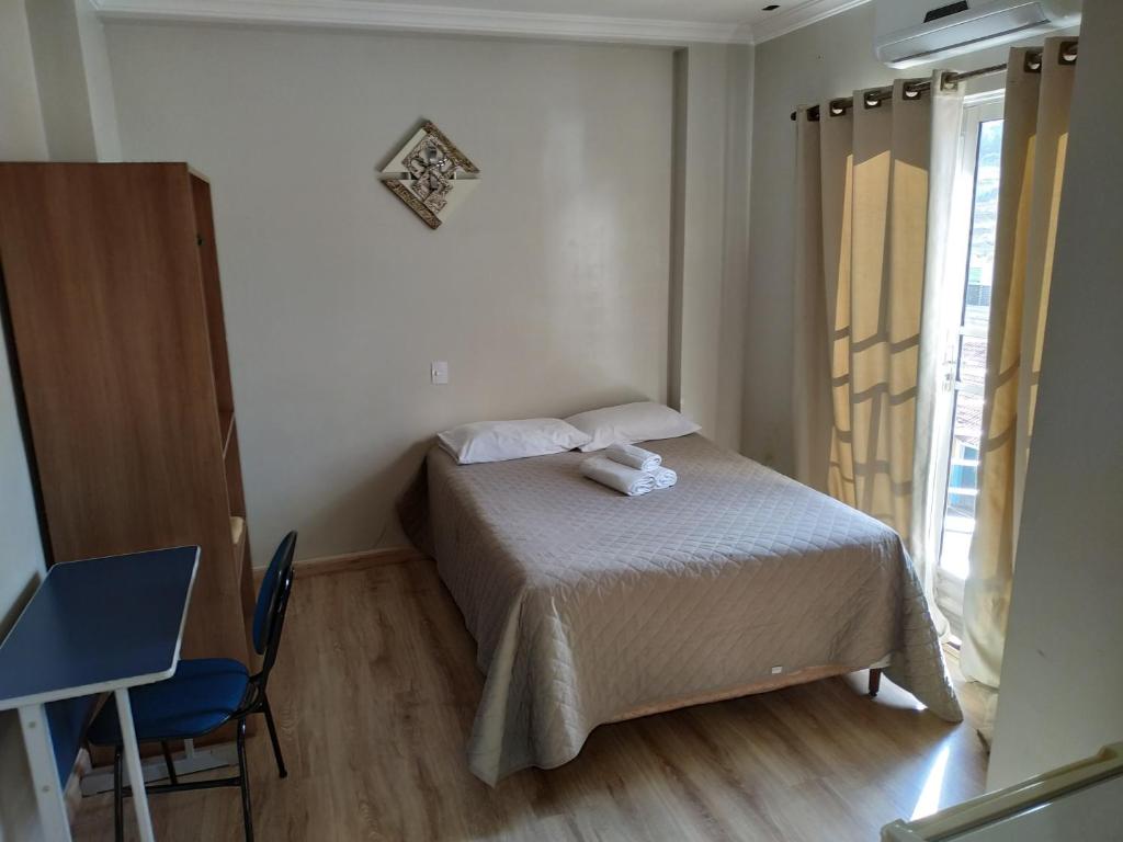 a bedroom with a bed and a chair and a window at Marinho Plaza Hotel in Capellinha