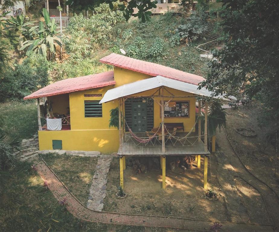 a small yellow house with a red roof at Finca Hostal Bolivar - Casa Maracuya in Minca