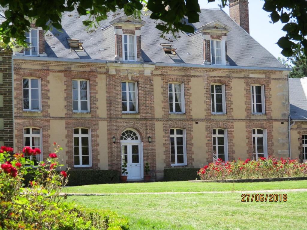 ein großes Backsteinhaus mit Blumen im Hof in der Unterkunft Le domaine de Beaufai in Beaufai