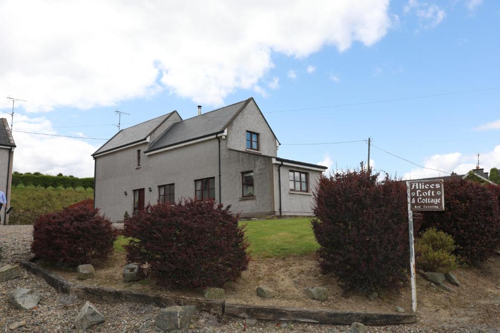 una casa blanca con un cartel delante en Alices Loft & Cottages, en Castleblayney