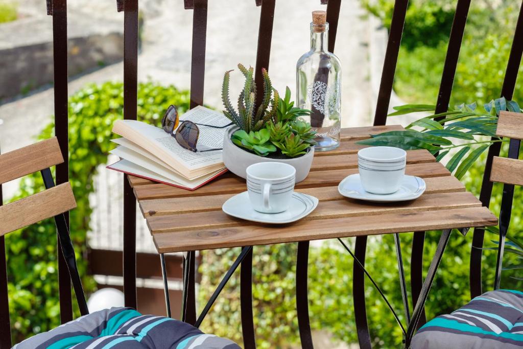 - une table en bois avec des tasses à café et des livres sur un balcon dans l'établissement AMI apartments, à Split