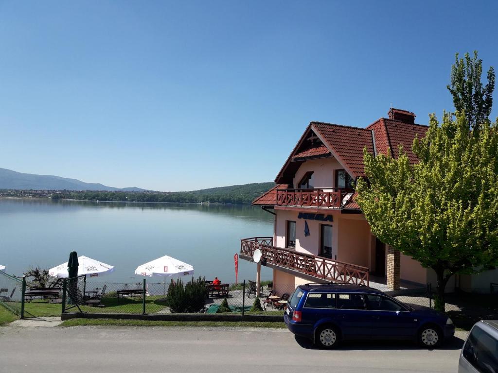 ein blaues Auto, das vor einem Haus neben einem See parkt in der Unterkunft O.W. LAZUR nad jeziorem in Żywiec