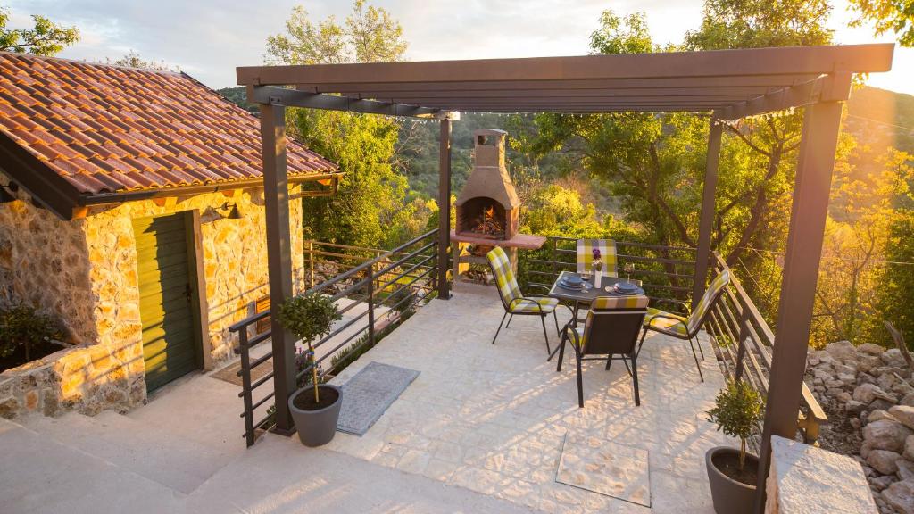 eine Terrasse mit einem Pizzaofen, einem Tisch und Stühlen in der Unterkunft Pelagia House in Zlarin