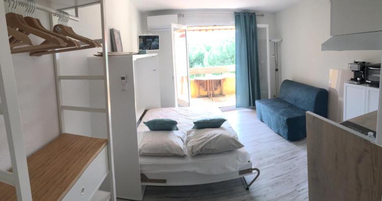 a small room with a bed and a living room at Studio rénové balcon ensoleillé et calme in La Londe-les-Maures