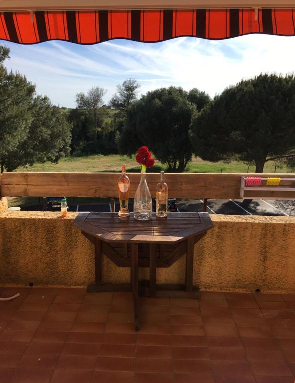 a table with two bottles and a vase with a flower on it at Studio rénové balcon ensoleillé et calme in La Londe-les-Maures