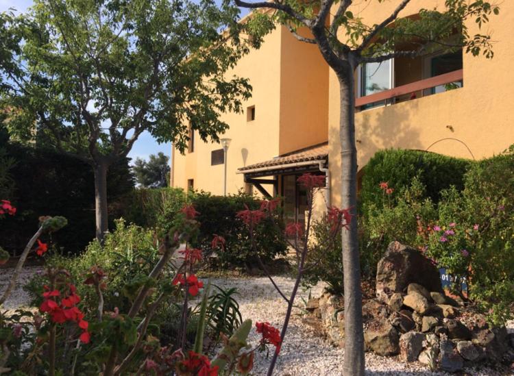a garden in front of a building with flowers at Studio rénové balcon ensoleillé et calme in La Londe-les-Maures
