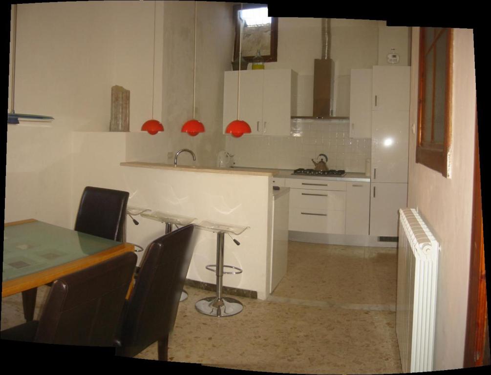 una cocina con mesa y sillas y una cocina con armarios blancos. en Penthouse Piazza d'Erba, en Orte