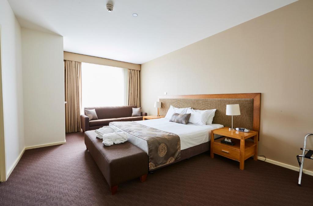 a hotel room with a large bed and a couch at Mornington Hotel in Mornington