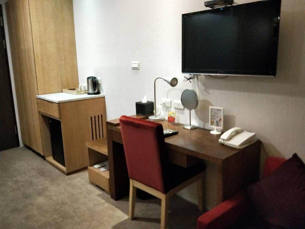 a room with a desk with a red chair and a television at In Young Hotel in Kaohsiung