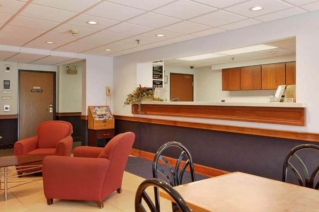 a waiting room with red chairs and a counter at Super 8 by Wyndham Manchester Airport in Manchester