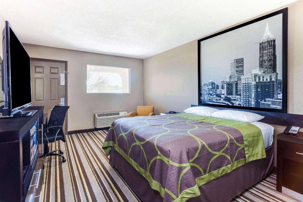 a hotel room with a bed and a flat screen tv at Super 8 by Wyndham Stockbridge in Stockbridge