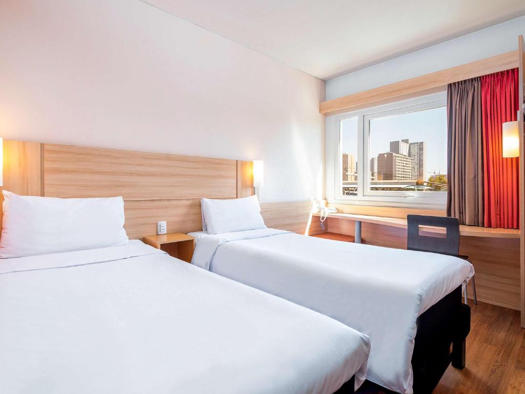 Una habitación de hotel con dos camas y una ventana. en ibis Santiago Estacion Central, en Santiago
