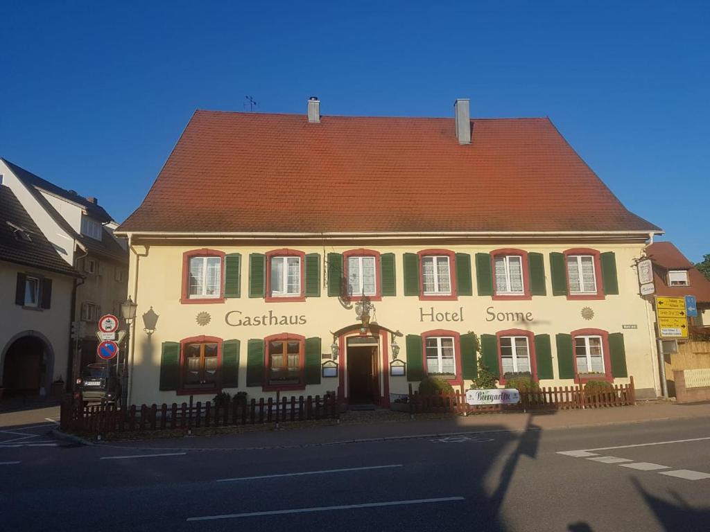 een groot geel gebouw met een rood dak op een straat bij Gasthaus Sonne in Schliengen