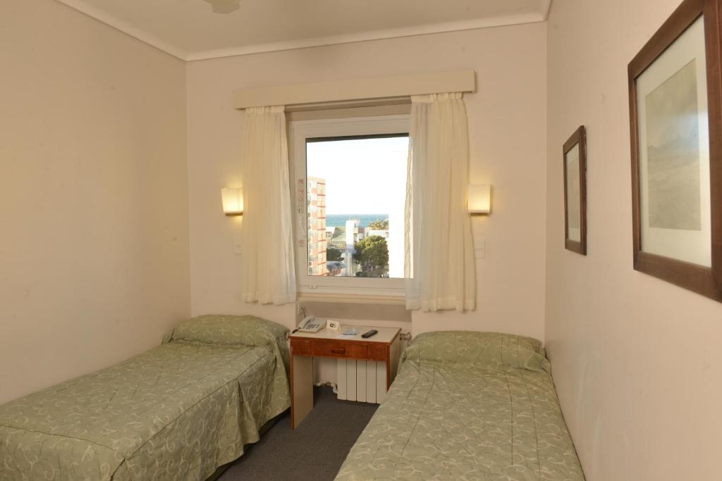 a hotel room with two beds and a window at Comodoro Hotel in Comodoro Rivadavia