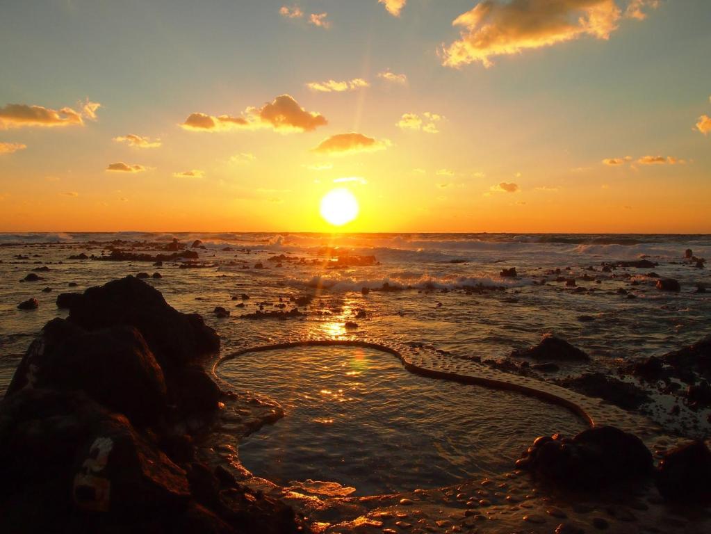 un tramonto sulla spiaggia con un cuore in acqua di Koganezaki Furofushi Onsen a Fukaura
