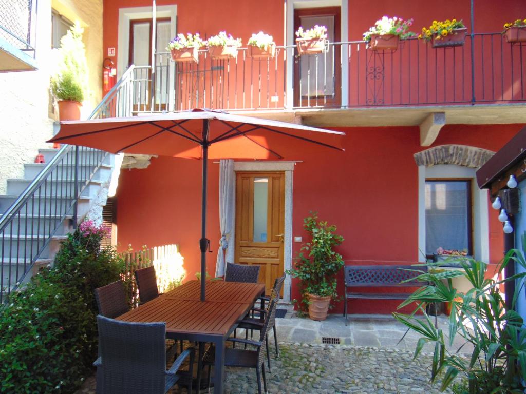 a wooden table with an umbrella in front of a house at B&B Antica Corte in Omegna