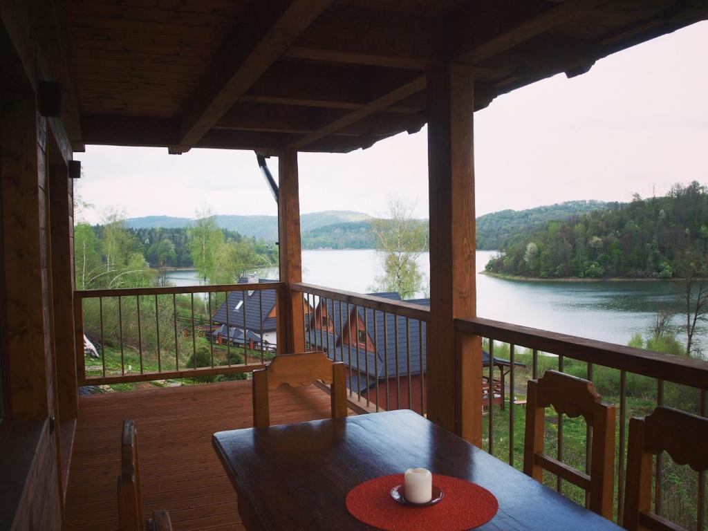 a table on a porch with a view of a river at Świerkowe Chatki in Olchowiec
