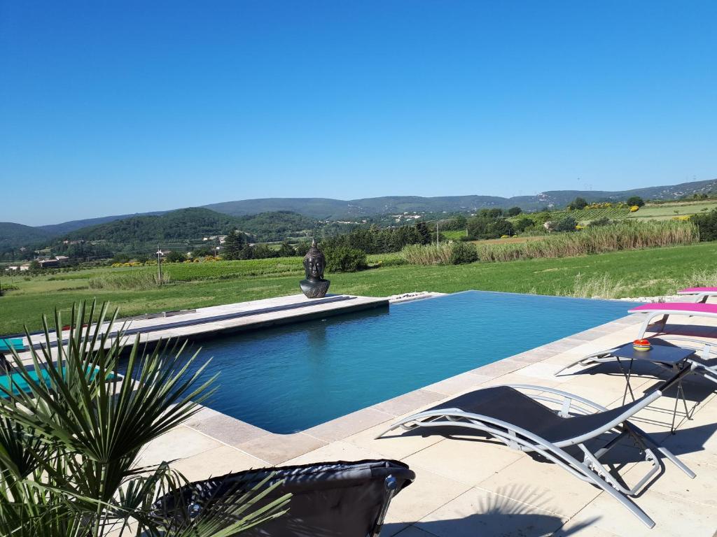 einen Pool mit zwei Gartenstühlen und einem Brunnen in der Unterkunft Le Mouleyras in Saint-Montan