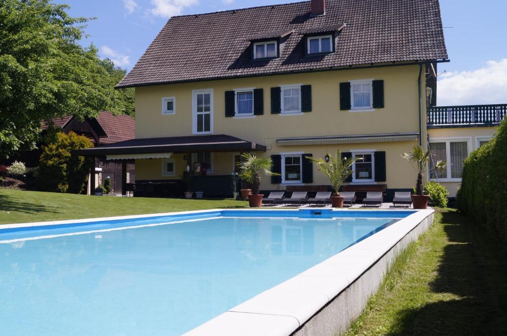 ein Haus mit einem Pool vor einem Haus in der Unterkunft Pension DOBERNIG - CONTACTLESS CHECK IN/STAY in Klagenfurt am Wörthersee
