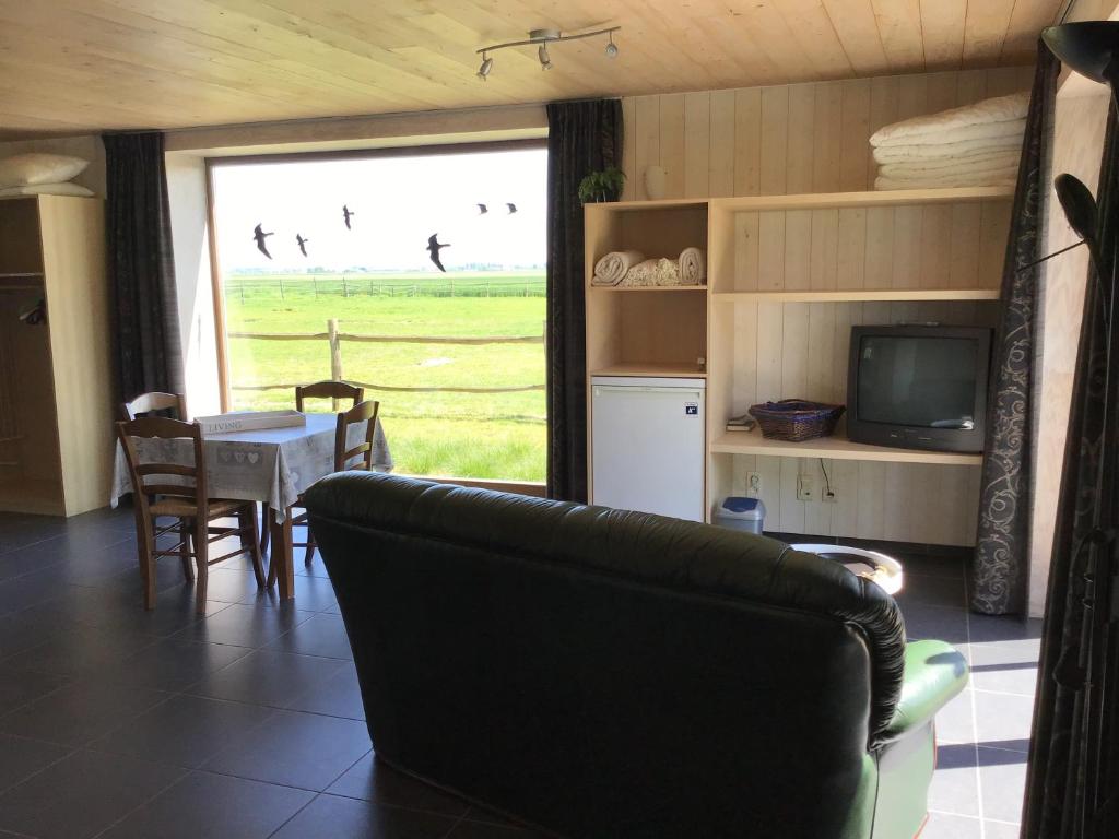 a living room with a couch and a table and a television at 't Moerlogie in Veurne