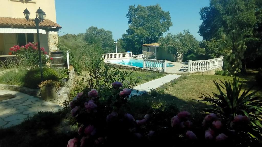 um jardim com uma ponte sobre uma piscina em Le mazet en été - studio en garrigue nimoise em Nîmes