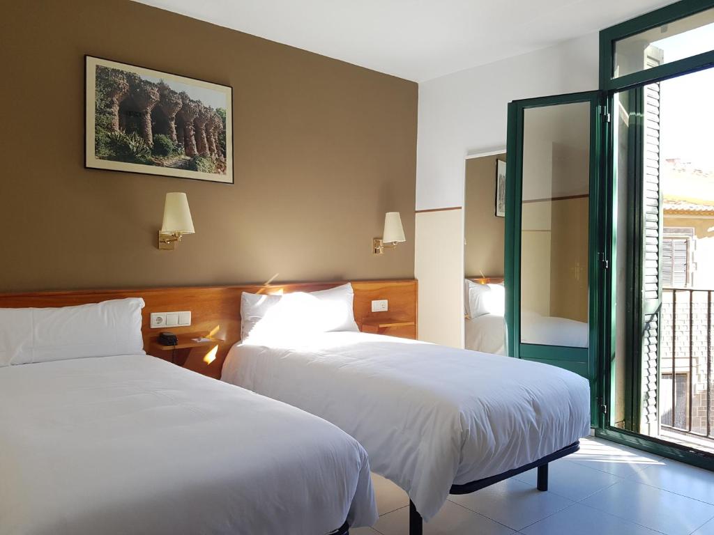 a hotel room with two beds and two windows at El Jardi in Barcelona