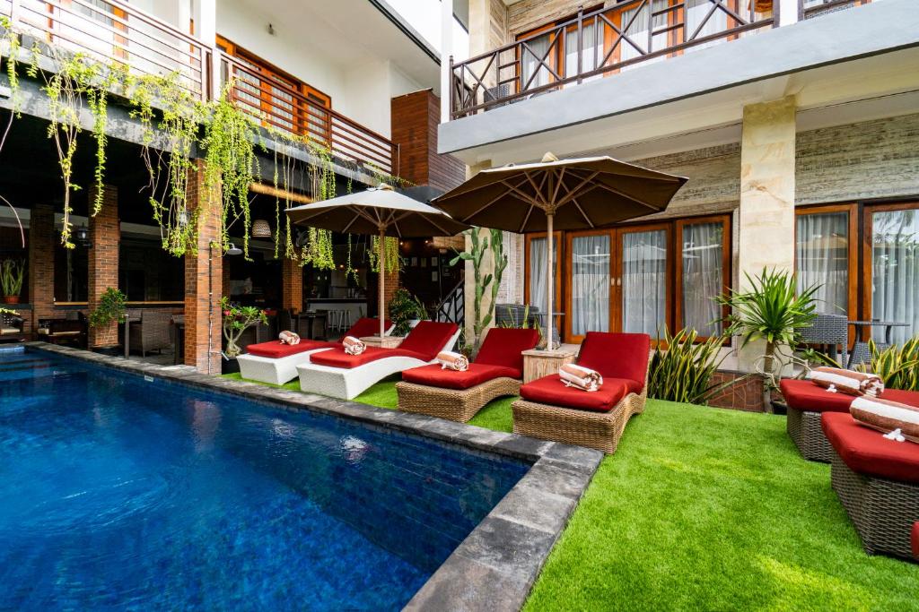 a pool with chairs and umbrellas next to a building at Nyuh Gading Home Stay in Nusa Lembongan