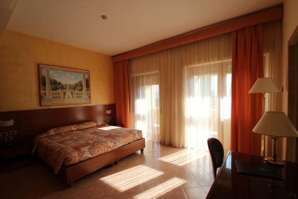 a bedroom with a bed and a desk and a window at Hotel Oasi Dei Discepoli in Orvieto