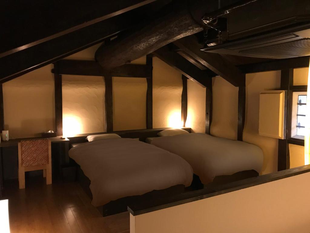 a bedroom with two beds and a table and a window at ShikiShiki Shinra in Kyoto