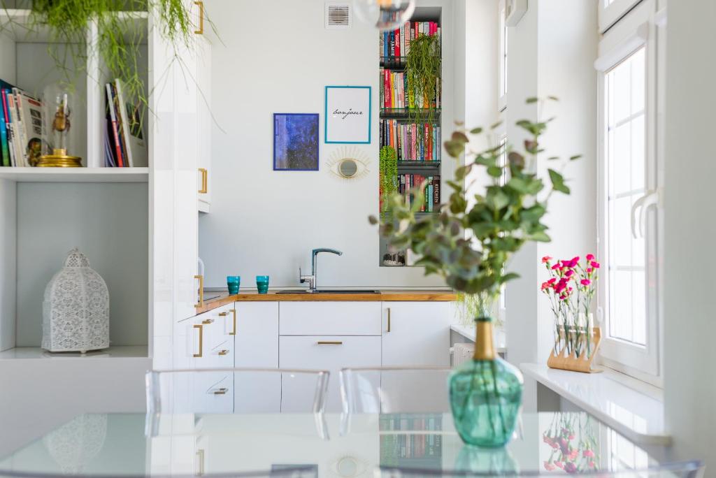 una cucina con tavolo in vetro e vaso con fiori di Hello Apartments Chlebnicka a Danzica