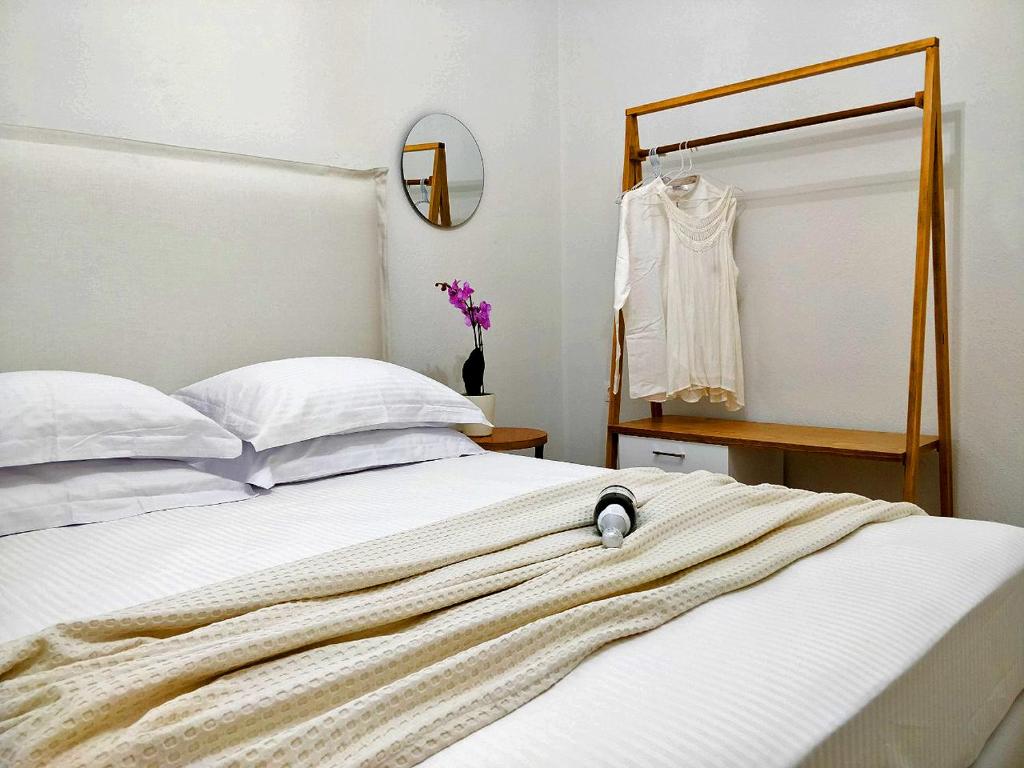 een slaapkamer met een wit bed, een spiegel en een jurk bij Sivilla Boutique in Afitos