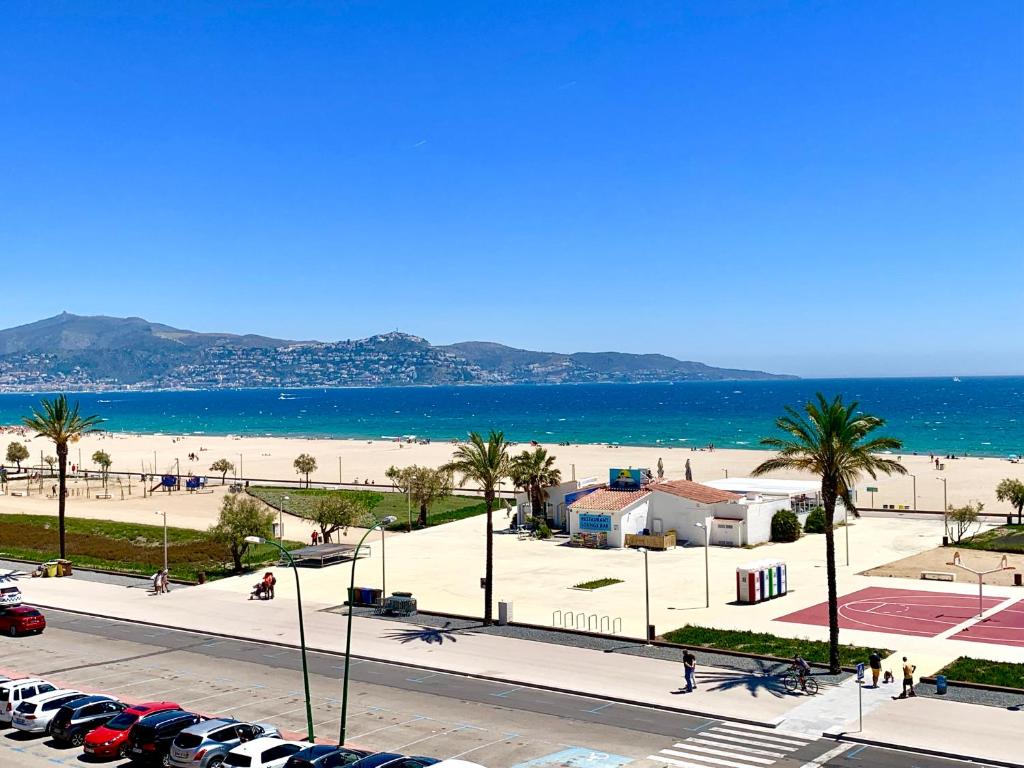 een uitzicht op het strand en de oceaan met geparkeerde auto's bij Edifici Valeria in Empuriabrava