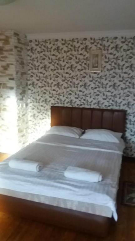 uma cama com lençóis brancos e almofadas num quarto em Комнаты рядом с автовокзалом em Uzhhorod