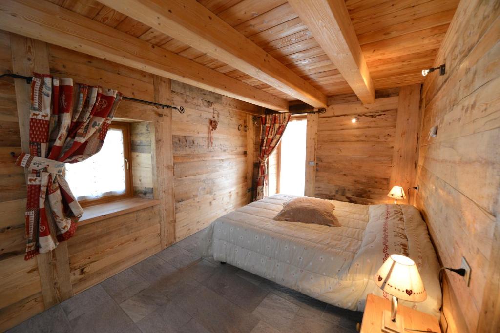 een slaapkamer in een blokhut met een bed bij Vieilles Maisons D'Introd in Introd