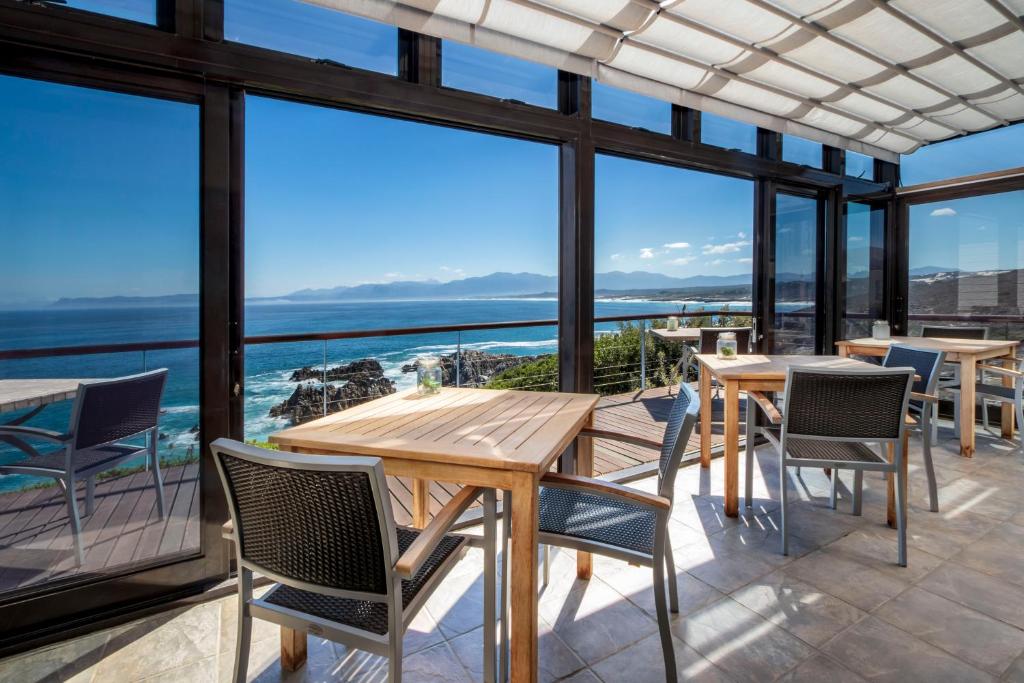 un patio con tavoli, sedie e vista sull'oceano di Cliff Lodge a Gansbaai