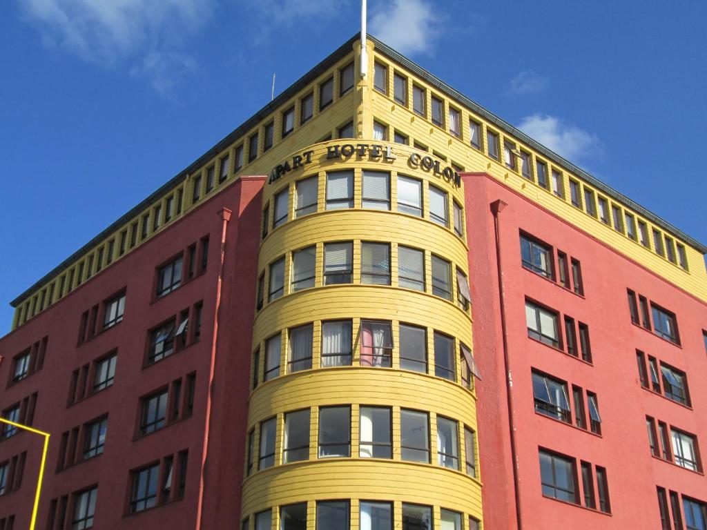 a tall yellow building with a flag on top at Hotel Apart Colón in Puerto Montt