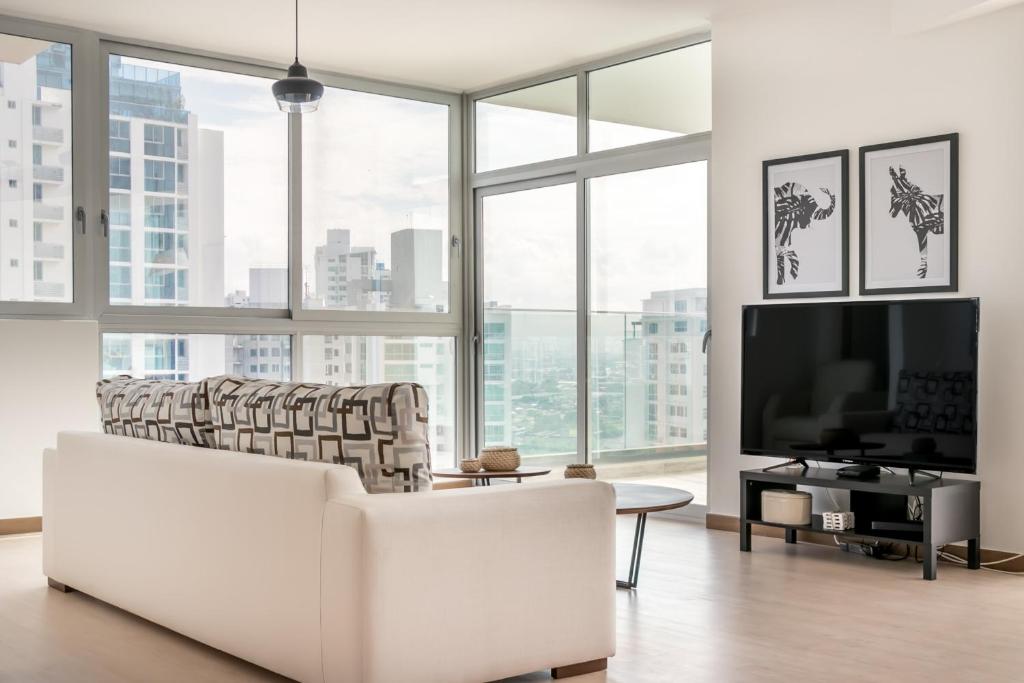 a living room with white furniture and large windows at Enchanting City View Apartment - PH Quartier Del Mar in Panama City