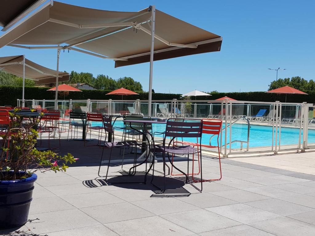 un patio con mesas y sillas y una piscina en ibis Styles Arles Palais des Congrès, en Arles