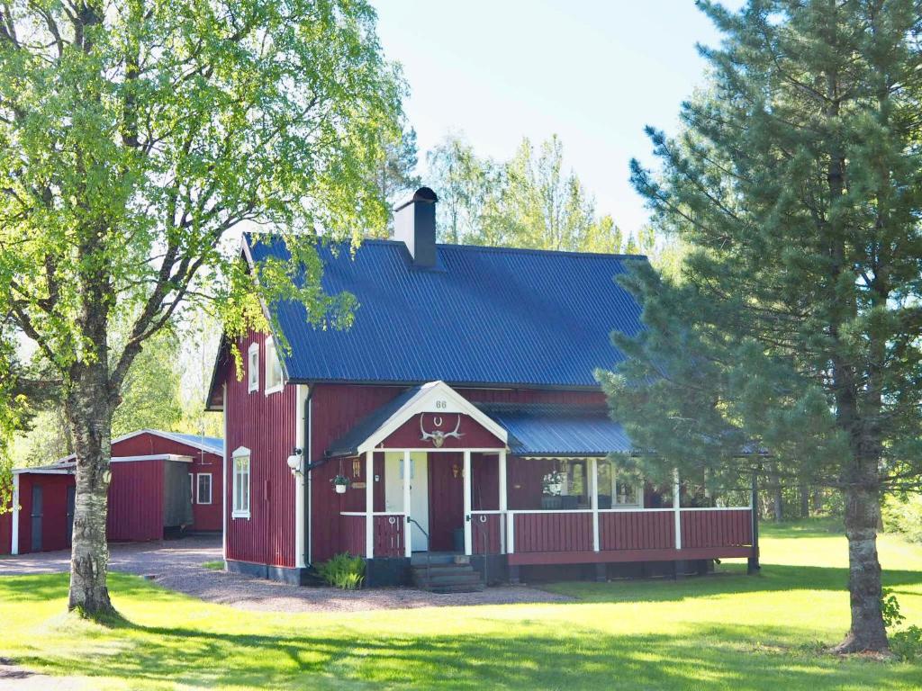 a red barn with a blue roof and trees at Orsastuguthyrning-Born in Orsa