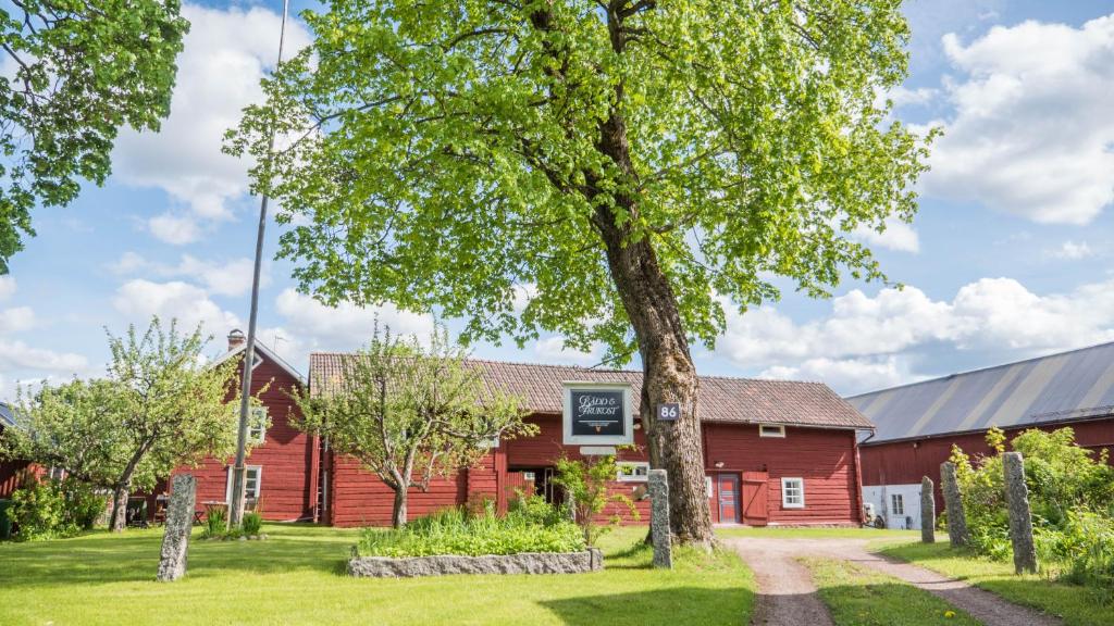 eine rote Scheune mit einem Baum davor in der Unterkunft Wikgården B&B in Gagnef