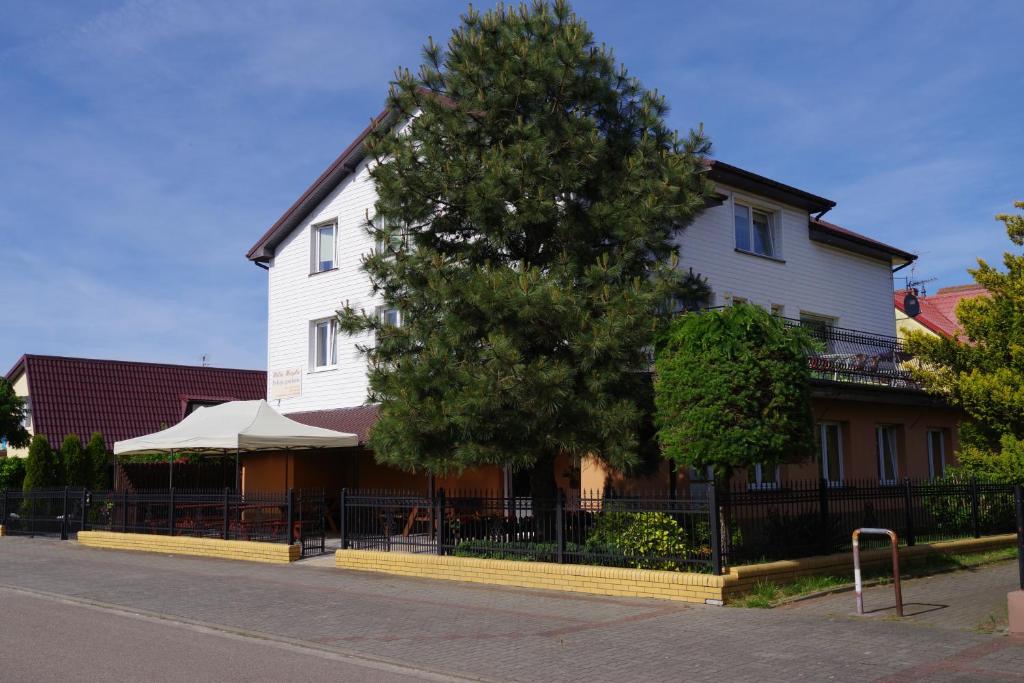 Un edificio blanco con un árbol delante. en Villa Magda, en Ustronie Morskie