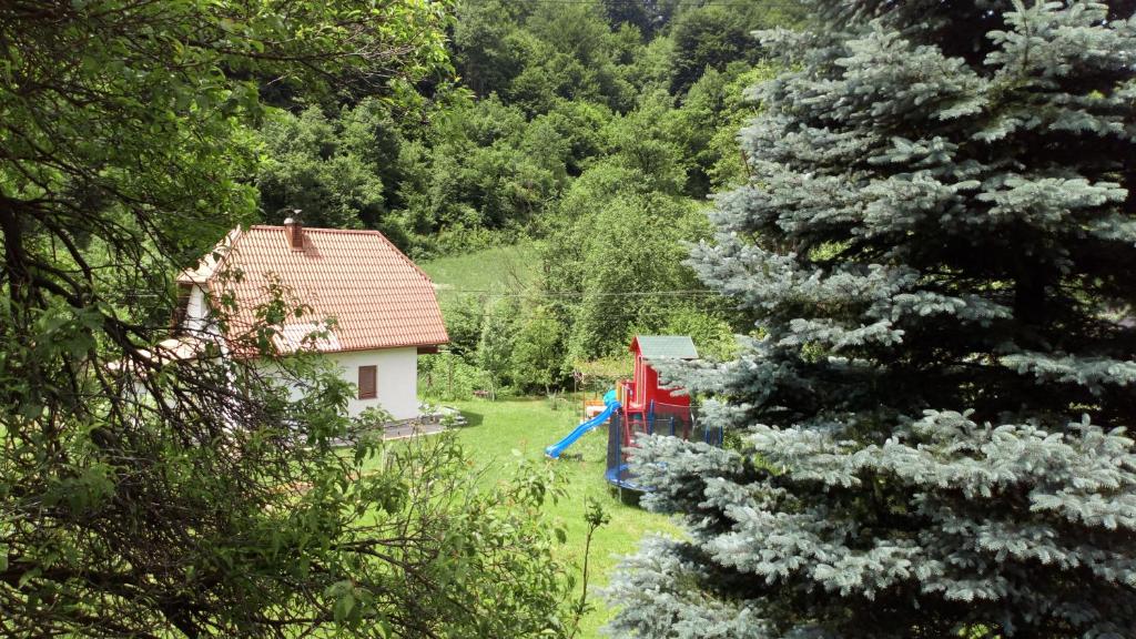 a house with a blue slide next to a tree at Cottage Forest Stream in Visoko